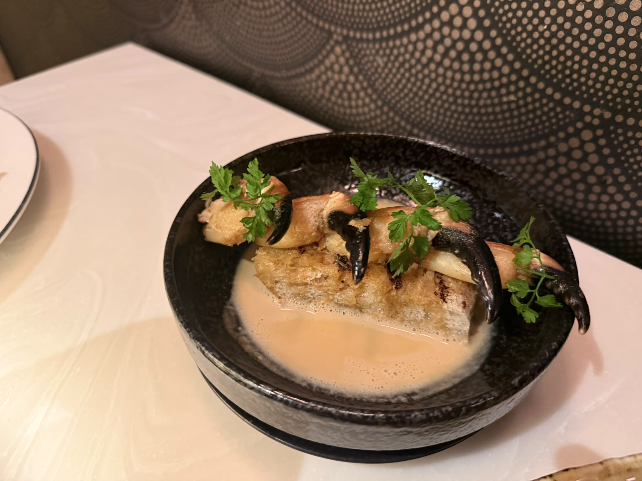 Crab claws on toast in a dark reactive-glaze bowl