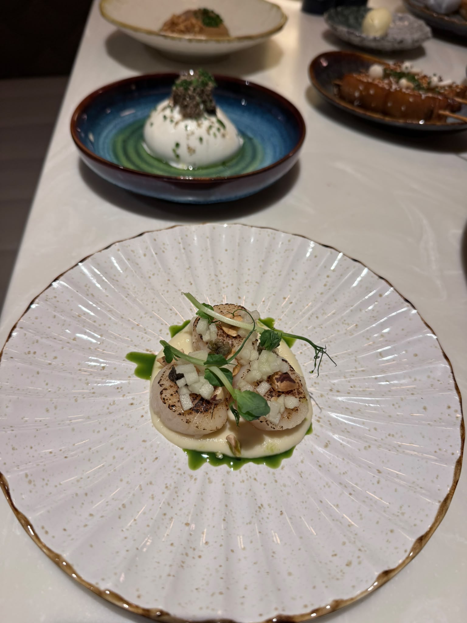 Seared scallops on a white fluted speckled plate