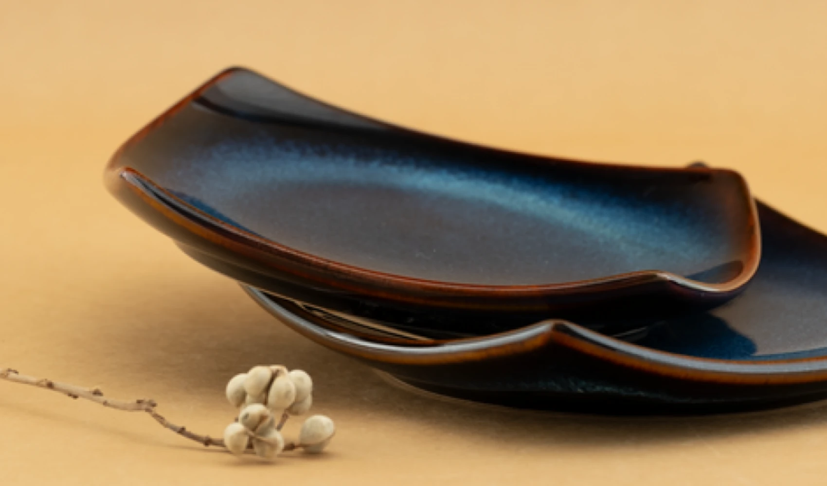 Two Blue Horizon square plates stacked, showing the indigo glaze and brown rim break
