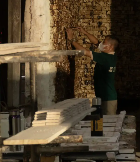 Craftsman shaping ceramic mosaic pieces in the workshop