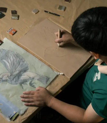 Artisan sketching a mosaic bird design on clay